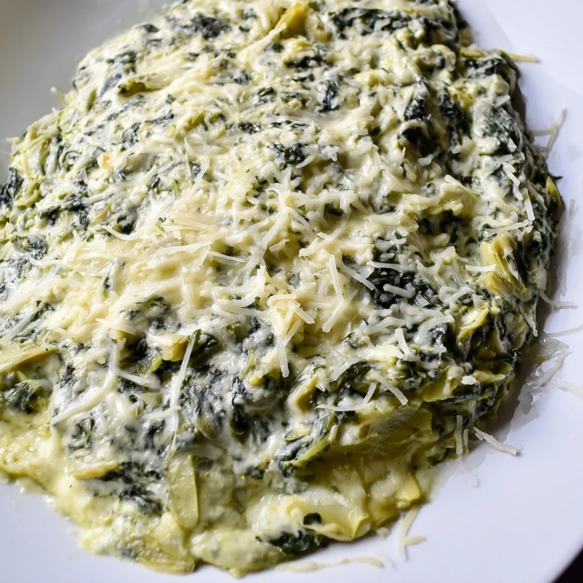 Golden, bubbly Cheesy Spinach Artichoke Dip, ready to be scooped up with crunchy tortilla chips at a party.