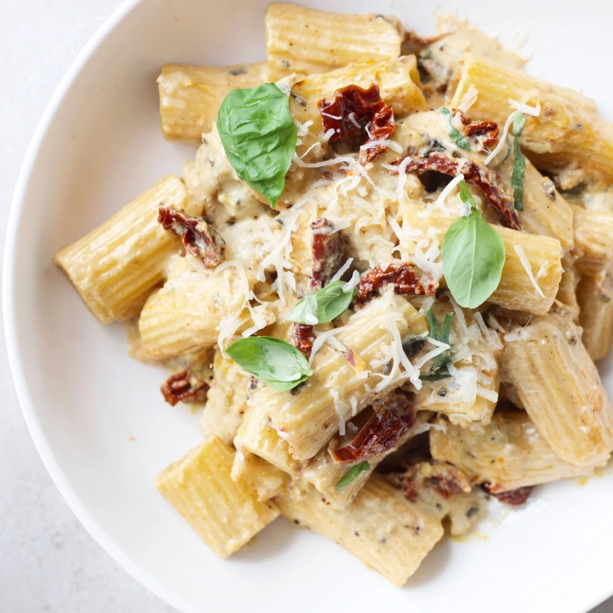 Creamy Sun-Dried Tomato Pasta, plated and ready, with fresh basil and Parmesan creating a beautiful aroma.