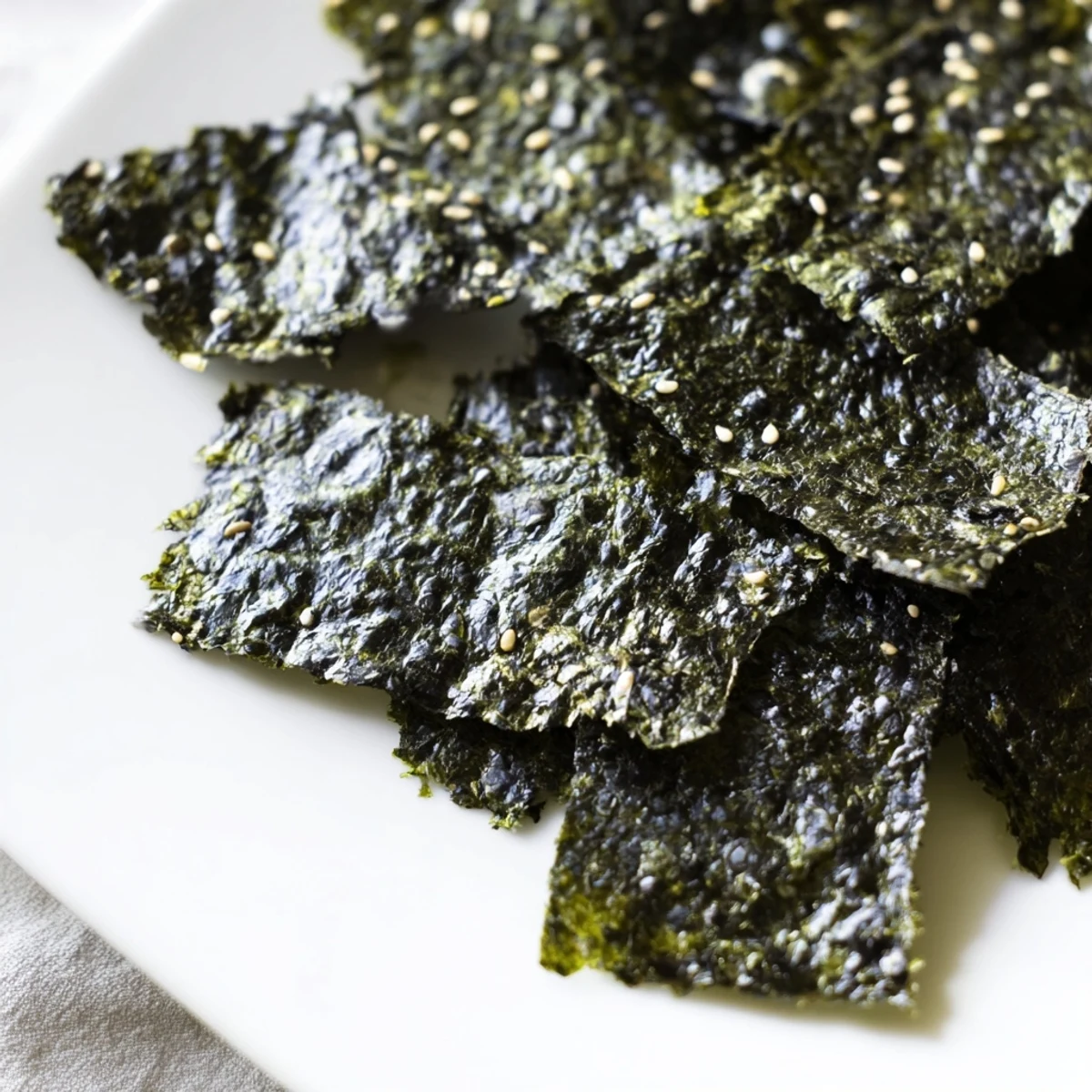 A close-up of golden roasted seaweed chips, lightly brushed with sesame oil and sprinkled with sea salt for a savory snack.