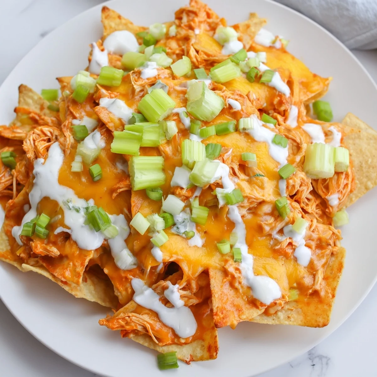 Crispy tortilla chips piled high with spicy buffalo chicken and melted cheese, finished with a creamy ranch drizzle and cilantro.