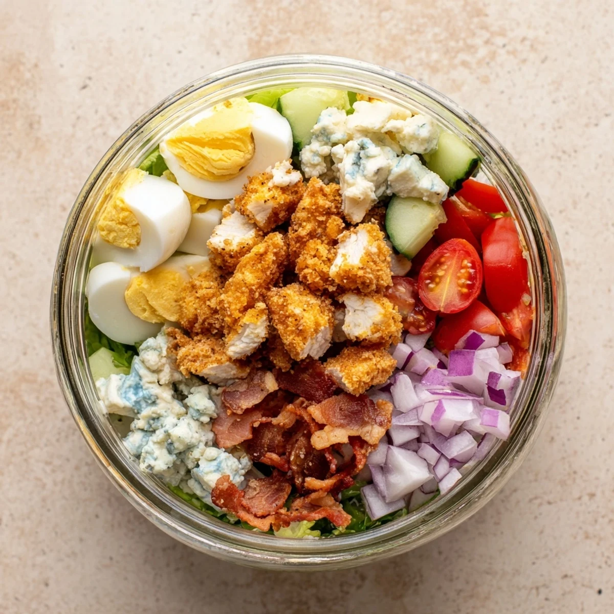 A top-down view of a vibrant Crispy Chicken Cobb Jar Salad, layered with golden chicken bites, bacon, and blue cheese.