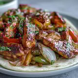 Sizzling, seasoned Easy Chicken Fajitas with colorful peppers and onions, ready to be scooped into warm, soft flour tortillas.