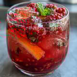 Refreshing raspberry lemon spritzer mocktail with zesty citrus and bubbly soda, garnished with mint.