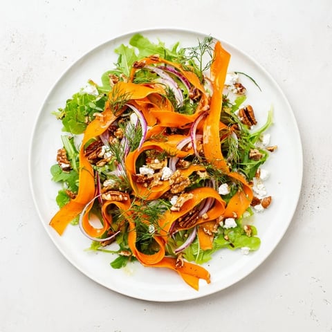 Tender roasted carrot ribbons rest on vibrant mixed greens, drizzled with honey-mustard vinaigrette and topped with feta.  