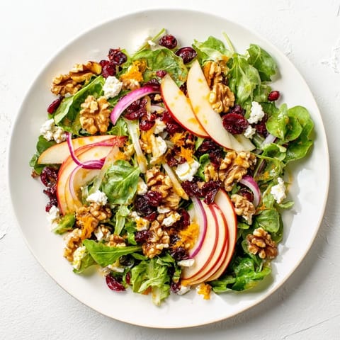 Showcasing a beautiful Seasonal Cranberry and Walnut Celebration Salad, ready to enjoy with a tangy orange vinaigrette drizzle.