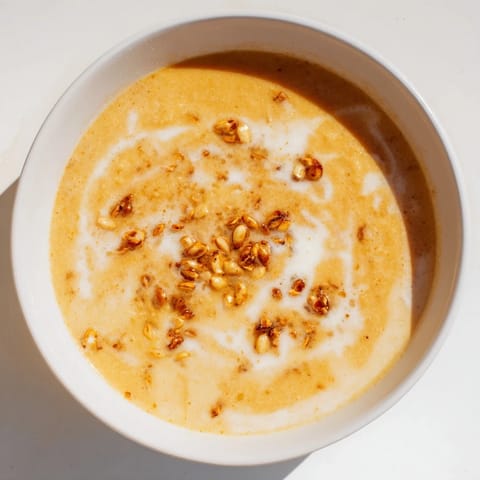 Aromatic creamy roasted pumpkin soup, perfect for an autumn meal, garnished with crunchy seeds.