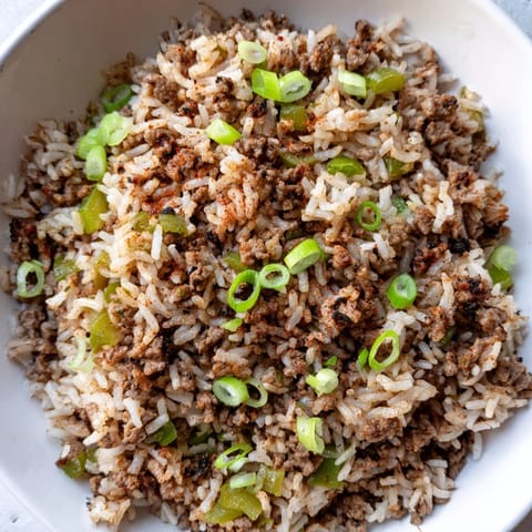 This vibrant photo shows cooked Cajun Dirty Rice, with visible vegetables and delicious savory aromas.