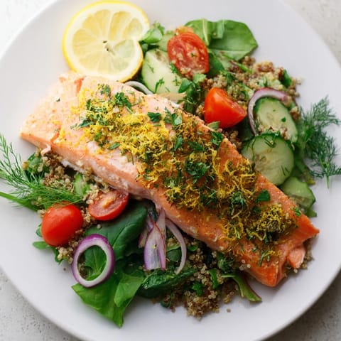 Lemon Herb Salmon Salad on a white plate features tender salmon fillet, fluffy quinoa, and crisp vegetables, drizzled with zesty lemon dressing.  