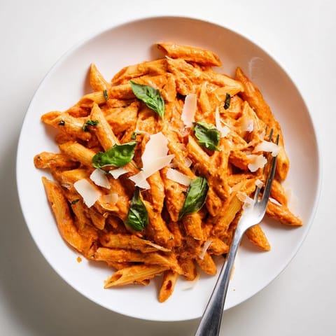 A close-up of Roasted Red Pepper Pasta with glossy, vibrant sauce, steam rising and garlic bread on the side.  