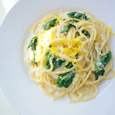 A close-up of Creamy Lemon Spinach Spaghetti twirled on a fork, highlighting the rich, velvety sauce coating the pasta.