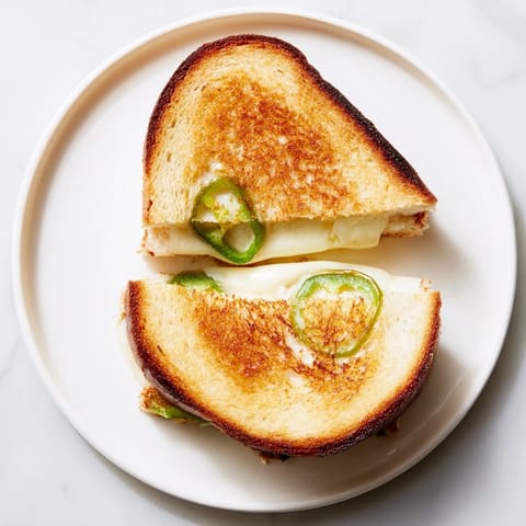 Golden, crispy sourdough grilled cheese with melted Havarti and vibrant jalapeño slices, served hot and ready to enjoy.