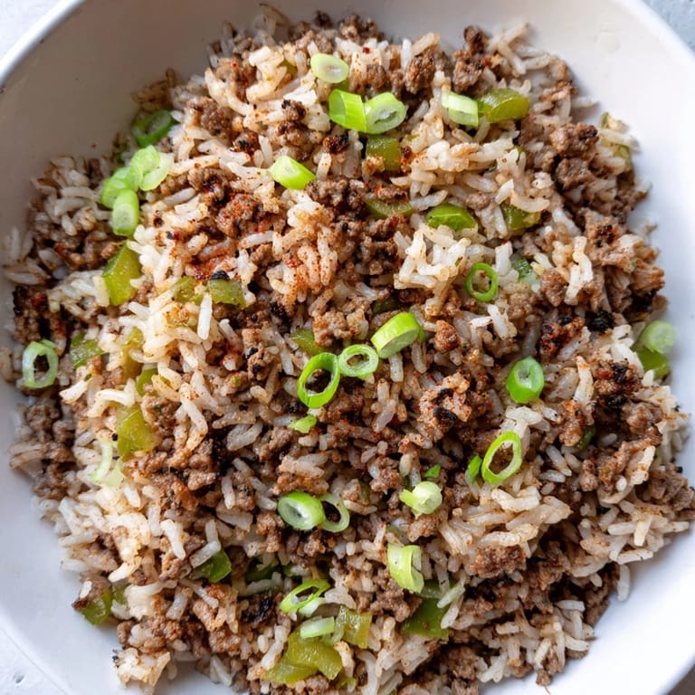 This vibrant photo shows cooked Cajun Dirty Rice, with visible vegetables and delicious savory aromas.
