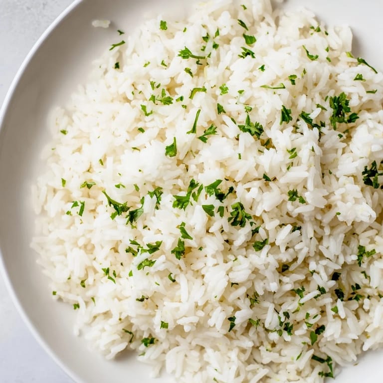Golden garlic butter rice glistening with melted butter, perfect alongside grilled chicken for dinner.