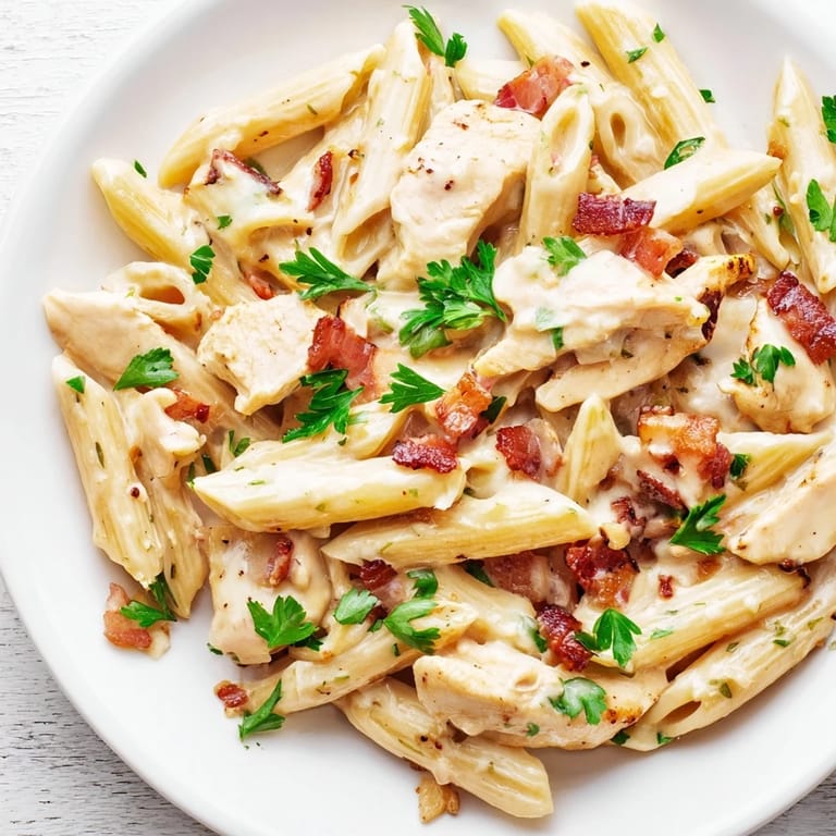 Creamy Chicken Bacon Penne plated in a skillet topped with grated Parmesan, ready to be served with a glass of wine.