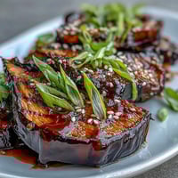 Silky roasted Miso Glazed Eggplant halves glistening with a rich, caramelized savory-sweet glaze and sprinkled with sesame seeds.